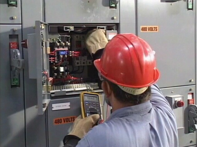 A worker demonstrating safe electrical work practices while working on an electrical panel