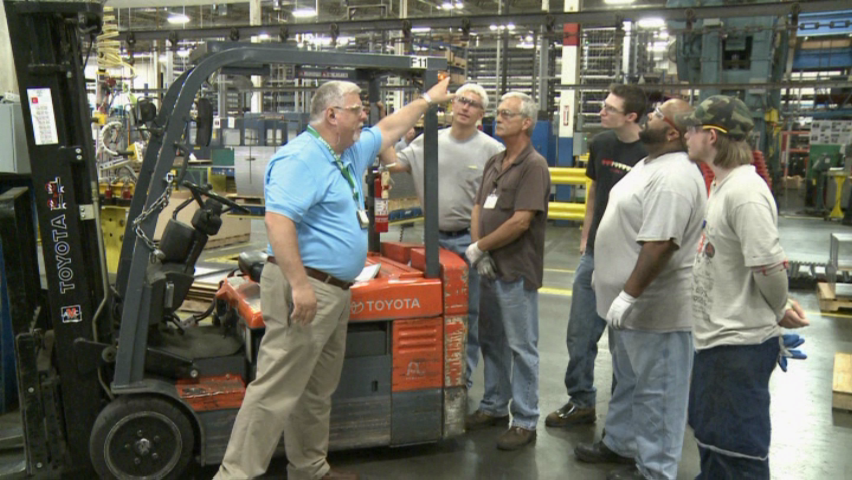 A forklift safety trainer describing safe operating procedures to a group of forklift operators