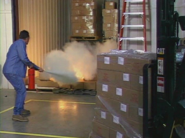 A worker that received proper training using a fire extinguisher to put out a fire in the workplace 