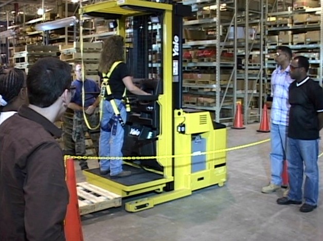 A safety trainer showing warehouse workers how to operate order selectors safely in the workplace