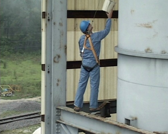 A worker using a personal fall arrest system properly to keep himself safe in case of a fall