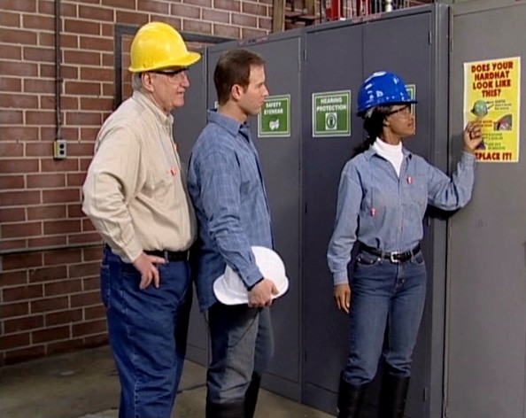 Workers reading a warning sign at work reminding them to always wear their hardhat in specific areas