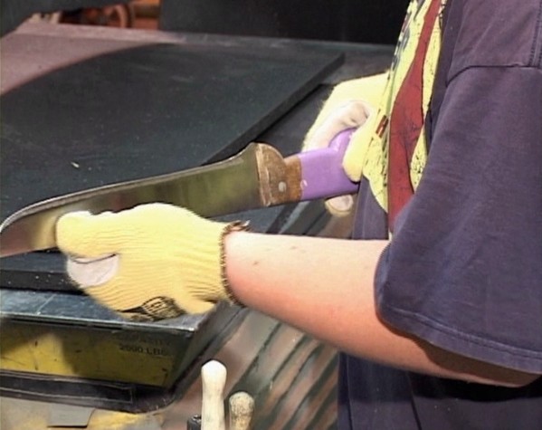 A worker demonstrating safe work practices while using an industrial knife to prevent injuries