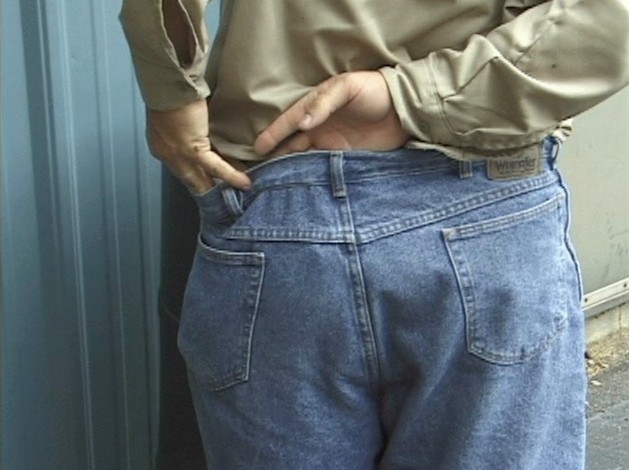 A worker demonstrating how to adjust loose clothing while at work to avoid serious injuries or death