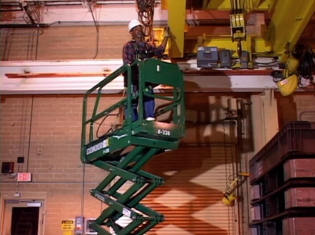 A worker on a scissor lift or aerial work platform using safe work practices to avoid injury