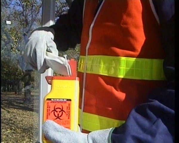 A worker preventing exposure to bloodborne pathogens by following safety training procedures