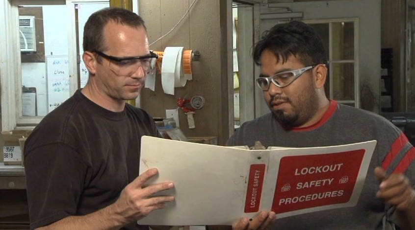 Two workers reviewing their company’s lockout / tagout or LOTO safety procedures to avoid injury