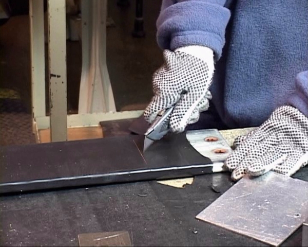 A worker following safe work practices while using a box cutter or utility knife to avoid injury