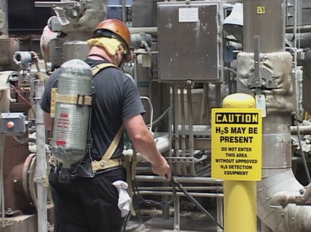 A worker wearing respiratory protection and following the Hydrogen Sulfide Contingency Plan