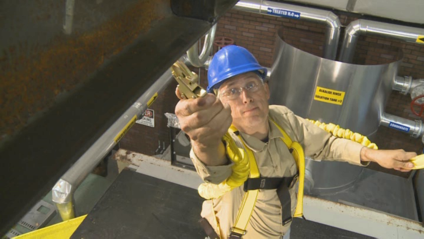 An industrial worker using a personal fall arrest system to illustrate the proper safety procedure