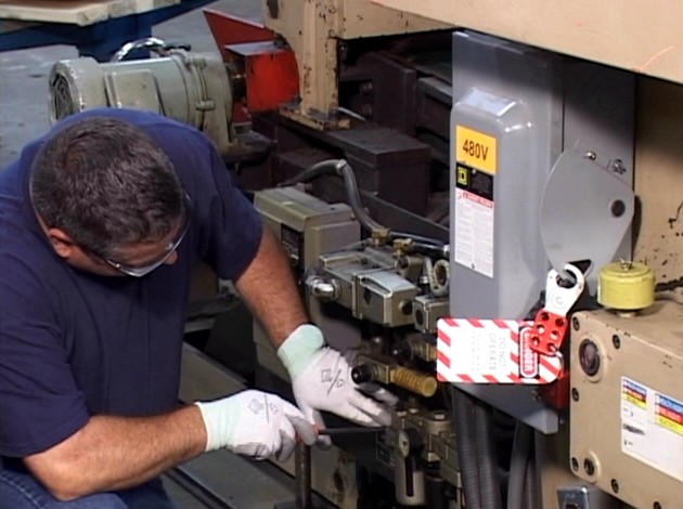 A worker controlling hazardous energy by following his lockout / tagout or LOTO safety training