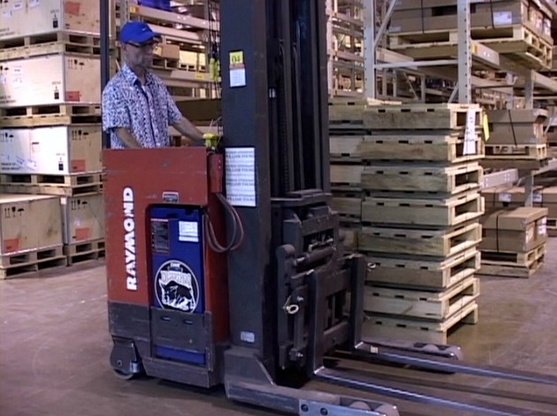 A warehouse worker safely operating a reach truck avoiding injury by following safe work practices