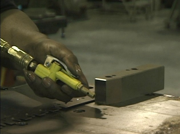 An industrial worker using compressed air in a safe manner to avoid serious injury at work