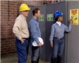 Workers reading a warning sign at work reminding them to always wear their hardhat in specific areas