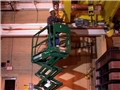 A worker on a scissor lift or aerial work platform using safe work practices to avoid injury