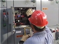 A worker demonstrating safe electrical work practices while working on an electrical panel