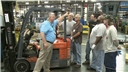 A forklift safety trainer describing safe operating procedures to a group of forklift operators