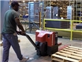 A warehouse worker safely operating an electric pallet jack to avoid injury in the workplace