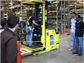 A safety trainer showing warehouse workers how to operate order selectors safely in the workplace