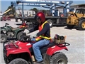 A worker demonstrating safe operating procedures while riding an all-terrain vehicle or ATV
